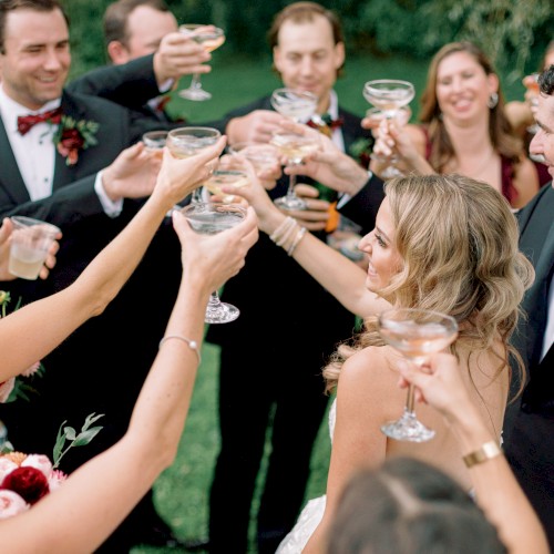 People toasting with drinks at a wedding celebration outdoors.