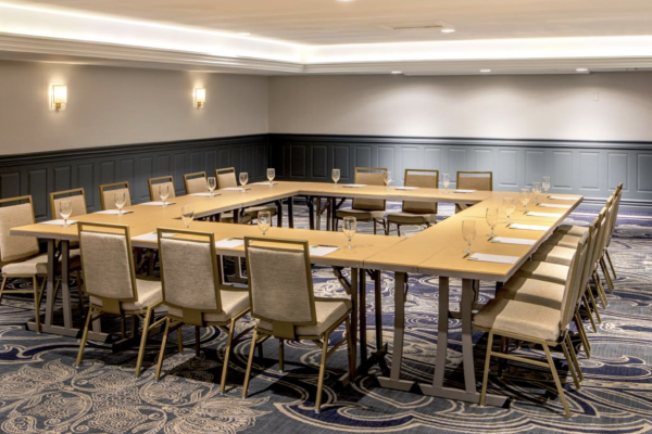 A conference room set up with chairs, glasses, and notepads arranged in a U-shape for a meeting or event.