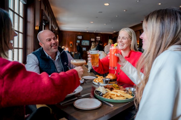A group of four friends enjoying drinks and a meal together in a cozy restaurant, sharing laughter and good times.