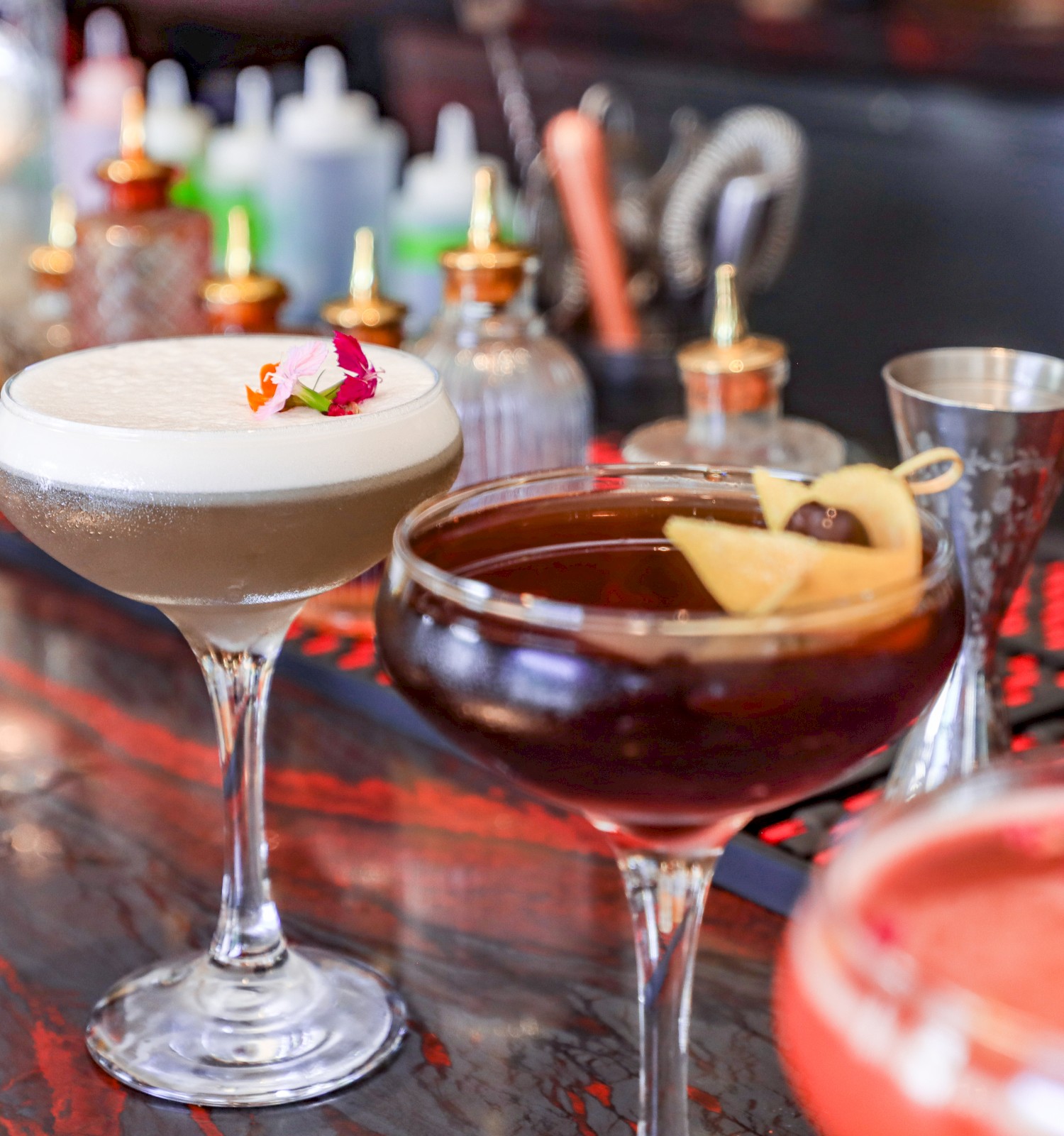 Three cocktails lined up on a marble bar top.