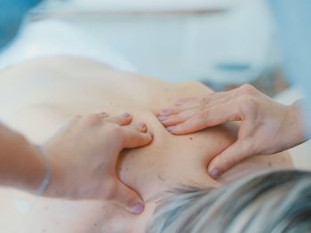 A person receiving a back massage, with hands pressing and kneading the muscles, promoting relaxation and stress relief.