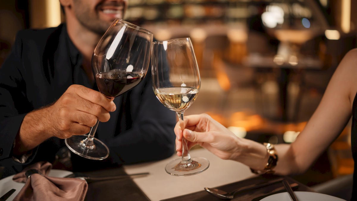 Two people sharing a toast at a restaurant, clinking wine glasses while enjoying a romantic dinner.