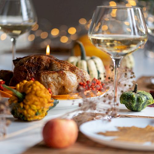 A Thanksgiving dinner table setup with roasted turkey, squash, wine glasses, and festive decorations, creating a cozy, autumn-themed ambiance.