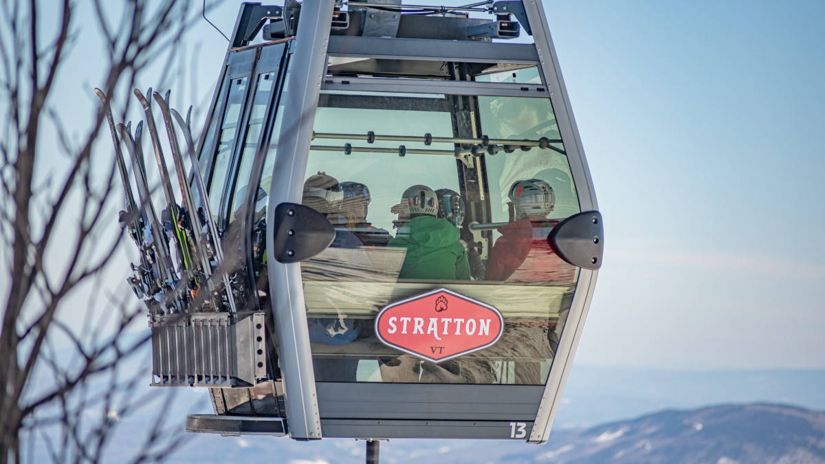 A gondola from Stratton Mountain, VT, carries skiers or snowboarders equipped with helmets and gear, ascending or descending a mountain.