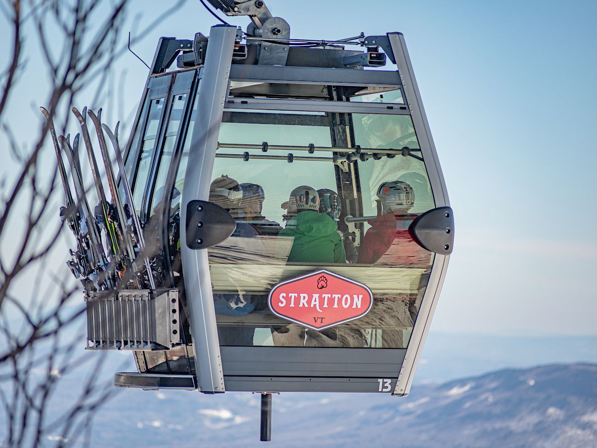 A gondola from Stratton Mountain, VT, carries skiers or snowboarders equipped with helmets and gear, ascending or descending a mountain.