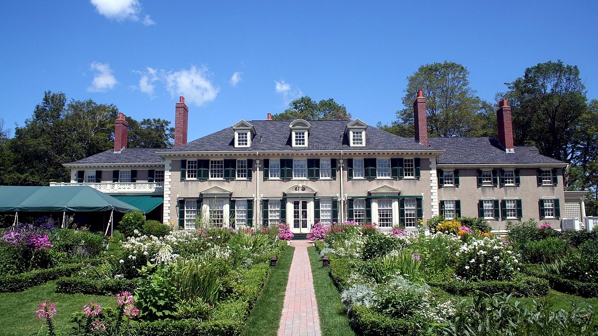 Exterior image of the Hildene Estate on a Sunny day. Surrounded by a manicured lawn and flowers in the spring.