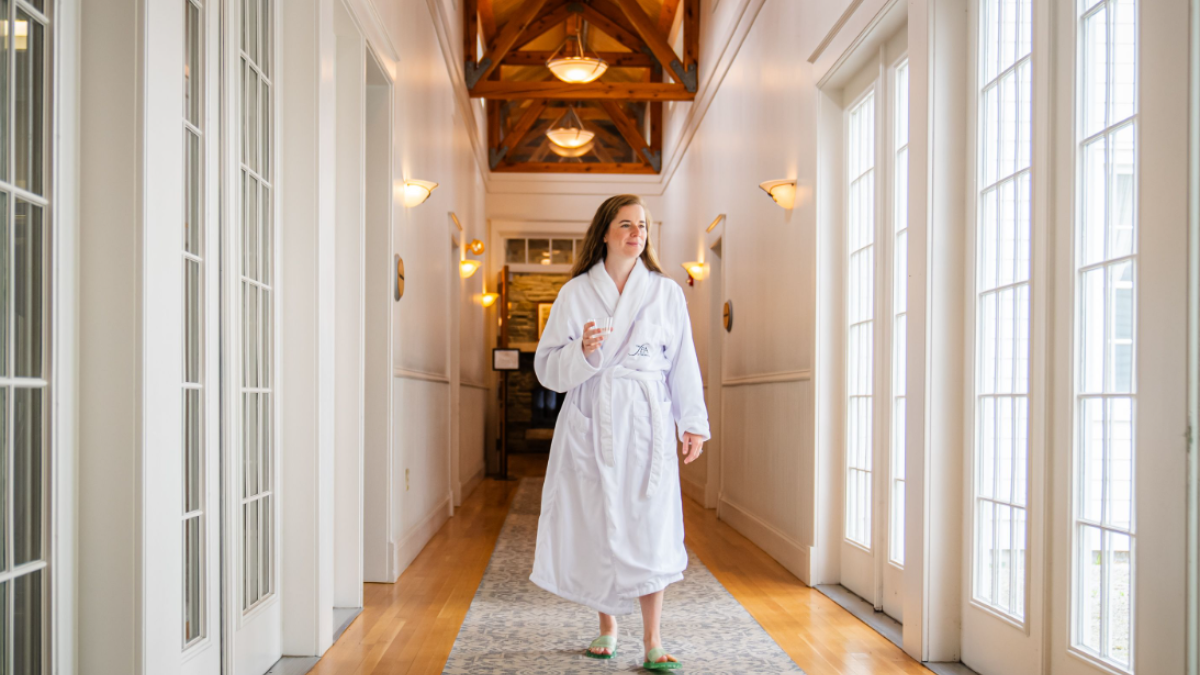 A women walking down the hallway of the Spa at Equinox in a white robe.