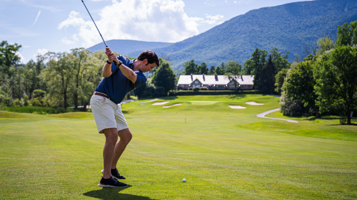 Older man swining golf club on a golf course.