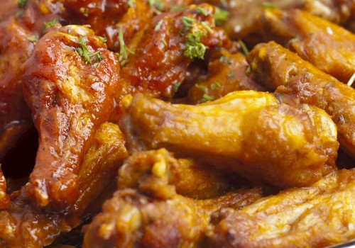 The image shows a plate of saucy chicken wings garnished with herbs.