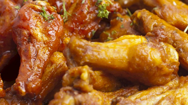 The image shows a plate of saucy chicken wings garnished with herbs.