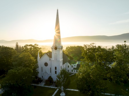 view of a church steple surrounded by lush greenery