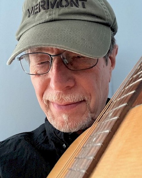 A person wearing glasses and a cap labeled 