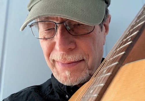 A person wearing glasses and a cap labeled 