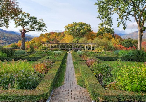 A beautifully landscaped garden with a brick pathway, surrounded by neatly trimmed hedges and colorful plants under a clear sky.