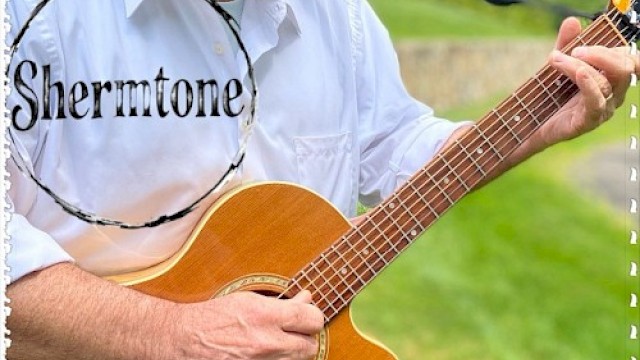 A person is playing an acoustic guitar outdoors with the text 