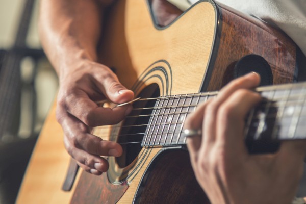 A person is playing an acoustic guitar, focusing on strumming and finger placement on the strings.