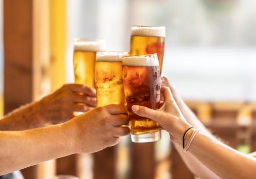 Four hands are toasting with glasses of beer, creating a cheerful and festive atmosphere.