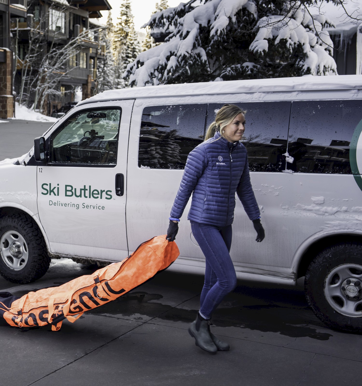 A person in winter attire carries an orange bag near a 
