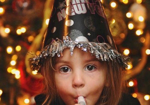 A child wearing a party hat and blowing a party horn at a festive celebration.
