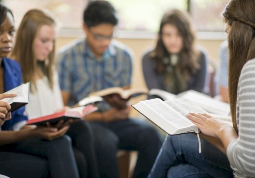 A group of students sits in a circle, reading books and sharing a discussion in a classroom setting.